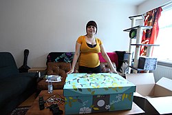 The maternity package, in neutral colors, is seen next to a mother expecting a baby.