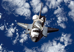 Backdropped by a blue and white Earth, Space Shuttle Discovery approaches the International Space Station.