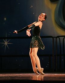 A dancer performs a "toe rise", in which she rises from a kneeling position to a standing position on the tops of her feet