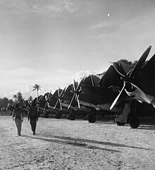 Marines walk past a flight line of SB2Cs on Falalop, December 1944 U.S. Marines on Falalop Island, Uluthi atoll - NARA - 520727 (cropped).jpg