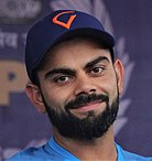 A photograph of a bearded man wearing blue coloured t-shirt and cap.