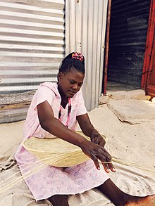 Frau webt auf dem Land in Namibia einen Korb auf traditionelle Art und Weise