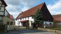 Farm with stable house (half-timbered partly plastered, partly boarded up), barn, courtyard paving and entrance pillar to the courtyard