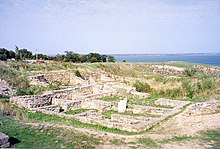 Remains of walls of small structures are seen in the foreground, while the Southern Bug estuary is seen in the background.