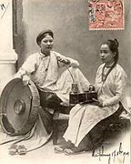 Two women wear áo ngũ thân, the form of the ao dai worn in the nineteenth and early twentieth centuries illustrated on a postcard