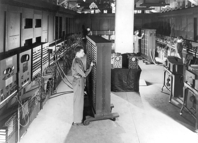 Cpl. Irwin Goldstein (foreground) sets the switches on one of ENIAC's function tables at the Moore School of Electrical Engineering. (U.S. Army photo)