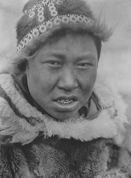 A Hooper Bay Askinarmiut boy poses wearing a circular cap (uivqurraq) and fur parka, photograph by Edward S Curtis (1930).
