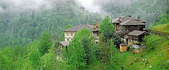 Casas em montanhas cobertas de neblina e árvores