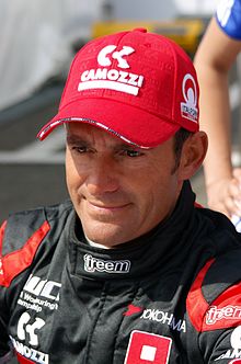 Portrait d'un homme souriant, en combinaison de course et avec une casquette rouge