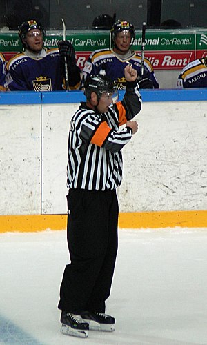 A referee signals a penalty for high sticking