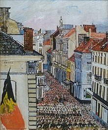 Eine Straßenszene, in der eine Musikkapelle den Umzug einer großen Menschenmenge durch eine enge Straße anführt, die von mehrstöckigen Häusern gesäumt ist. Im Vordergrund ist eine schwarz-gelb-rote Fahne zu sehen.