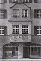 Zweistöckiger Erker in der Nadlerstraße 10 (früher 5) in Stuttgart mit Bildhauerschmuck von de:Josef Zeitler, 1906–1909. Die Brüstung ist im ersten Stock mit drei schmalen Reliefstreifen geschmückt, die zwei Relieftafeln flankieren. Die Reliefs zeigen Szenen aus Eduard Mörikes Stuttgarter Hutzelmännlein. Szene 1 (von links nach rechts): am Stadttor (halb zerstört), 2: das Hutzelmännlein erscheint dem Schustergesellen Seppe, 3: Die schöne Lau, 4: Seppe trifft seine spätere Verlobte Vrone auf dem Hochseil, 5: der Rathausbrunnen. Der übrige Teil des Erkers war mit Ritzzeichnungen verziert, die später überputzt wurden. Foto: 1909.