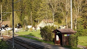 Single-line railway line next to a platform with a wooden shelter