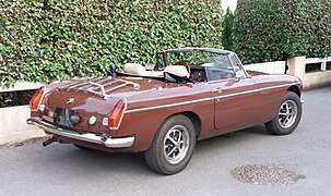 Une superbe MG B couleur chocolat, avec un porte-bagages de type "véronique" sur le coffre.