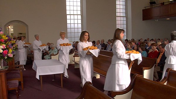 Moravian dieners serve bread to fellow members of their congregation during the celebration of the lovefeast at Bethania Moravian Church in North Caro