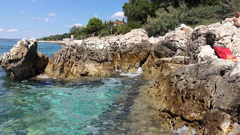 File:Novi Vinodolski, pogled s plaže na stijene.jpg