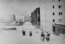 Four Finnish soldiers, with their backs shown, are retreating to the demarcation line after the ceasefire came into effect. The city of Viipuri looks empty and smoke is rising in the background.