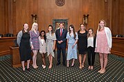 Photo de groupe de huit femmes et un homme, debouts, dans une salle officielle américaine.