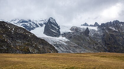 Maciço Sofia (3 637 metros) e geleira Sofia em meio a nuvens e neblina sob neve fresca de outono. Carachai-Circássia, cordilheira do Cáucaso. Sofia é o segundo pico mais alto do Arkhyz e está localizado a menos de 7 km da fronteira com a Geórgia. A montanha é cercada por um vale a leste e a oeste. A geleira Sofia está localizada na montanha. Várias cachoeiras descem das encostas de Sofia, formando o turbulento rio Sofia. Há também os pitorescos lagos de Sofia nas encostas. O maciço Sofia atrai muitos turistas, amantes da natureza e montanhistas. (definição 4 912 × 2 760)