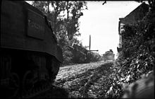 British Sherman tanks pass a knocked out Tiger tank The British Army in the Normandy Campaign 1944 B6156.jpg