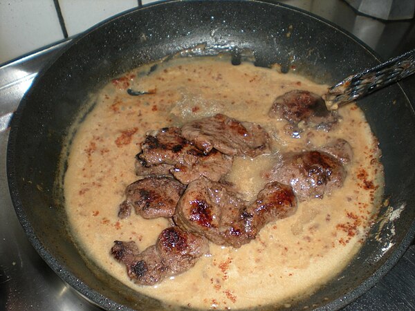 Venison escalope cooking in sauce