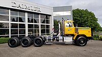 Yellow day cab Western Star 6900. Tri-drive rear axles with single steer axle, and equipped with a fifth wheel.