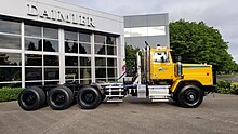 Yellow day cab Western Star 6900. Tri-drive rear axles with single steer axle, and equipped with a fifth wheel.