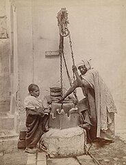Algerian man and boy drawing water from a well (circa 1892)