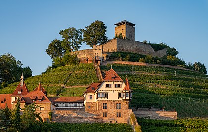 Vista do castelo Hohenbeilstein (acima), um castelo no topo de uma colina acima da cidade de Beilstein, no extremo sul do distrito de Heilbronn, em Baden-Württemberg, Alemanha. Suas origens estão no século XI; os componentes mais antigos ainda visíveis hoje datam do século XIII. Sitiado e destruído várias vezes, inclusive por fazendeiros rebeldes em 1525 e na Guerra dos Nove Anos (1688 a 1697) pelos franceses. O castelo hoje consiste de uma torre de menagem pentagonal de 28 metros de altura, que pode ser escalada como uma torre de observação, uma muralha de proteção de 2,5 metros de espessura e vários edifícios anexos na área do pátio externo, que agora são usados ​​como falcoaria e restaurante. O Unteres Schloss (abaixo) está localizado a meio caminho entre a vila e o castelo Hohenbeilstein. Ele consiste de um pátio construído no século XVI, no local do qual uma casa de campo foi construída entre 1906 e 1908 em estilo historicista para o industrial têxtil Robert Vollmöller. O Unteres Schloss é o centro de conferências da Igreja Evangélica em Württemberg desde 1957, que é proprietária do edifício desde 1959. (definição 7 487 × 4 736)