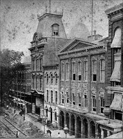 Washington Street entrance before the fire, looking north toward Johnson Street. The theatre is distinguished by its mansard roof; its L-shaped lot wrapped around the Dieter Hotel, here partially obscured by trees. Brooklyn Theatre.jpeg