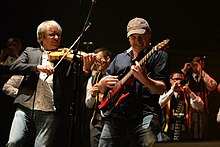 Violoniste et guitariste de Red Cardell devant les sonneurs de bombardes du bagad.