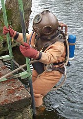 Helmeted diver entering the water. He has a back mounted Draeger DM40 rebreather system in addition to the surface supply air hose (2010) DM40 thm.jpg