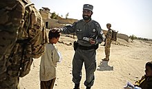 An Afghan police officer pats a child on the head. Defense.gov photo essay 110926-F-RN211-071.jpg