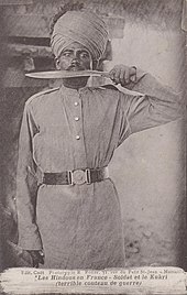 Moustasched Hindu Gorkhali soldier with Khukuri-in-mouth pose photographed in 1915 Gorkha with Khukuri 1915.jpg