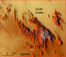 Carte de relief en nuances de couleurs chaudes, montrant au centre une masse montagneuse principale en orange et blanc, mesurant dans la réalité environ 55 km sur 30. D'autres plus petits massifs sont présents en haut à gauche et à droite.