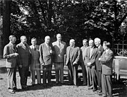 Fotografia em preto e branco de dez homens em ternos de gravata.