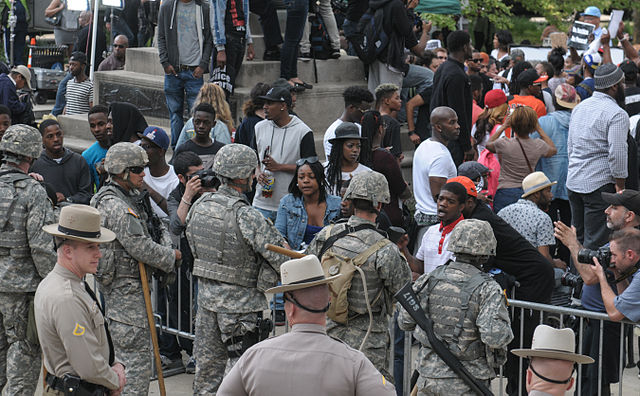 Maryland Army National Guardsmen watching protesters gathered in front of Baltimore City Hall, 30 April 2015