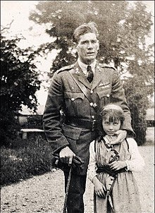 Photographie noir et blanc. Mannock est debout et sa main gauche est au niveau du visage de la petite fille.