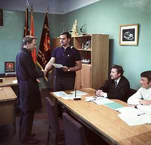 English: Komsomol Committee Secretary Gorodetsky handing over a merit certificate to Mikhailov, mechanic of press room number one Русский: Секретарь комитета комсомола Городецкий вручает грамоту механику прессового цеха № I Михайлову