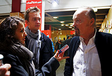 Deux étudiants de l'institut de Rennes interviewent Alan à droite à l'aide d'un téléphone aux couleurs du drapeau américain.