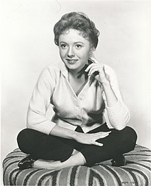B&W image of smiling actress sitting cross-legged on cushion