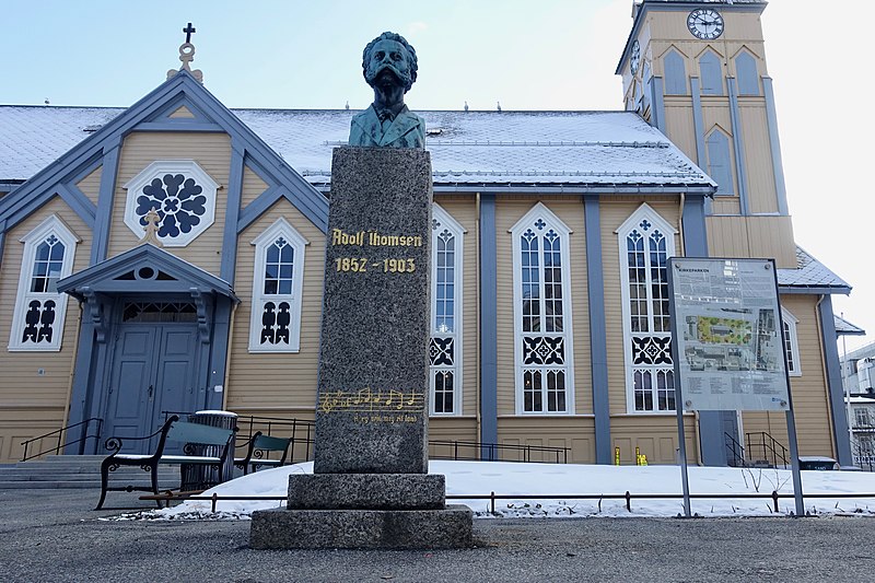 Fil:Tromsø Cathedral (domkirke) Norway Adolf Thomsen monument by Trygve Thorsen 1943 unveiled 1946 (Å eg veit meg eit land), Kirkeparken info board, Wooden Gothic Revival style long church 1861 2019-04-04 DSC02177.jpg