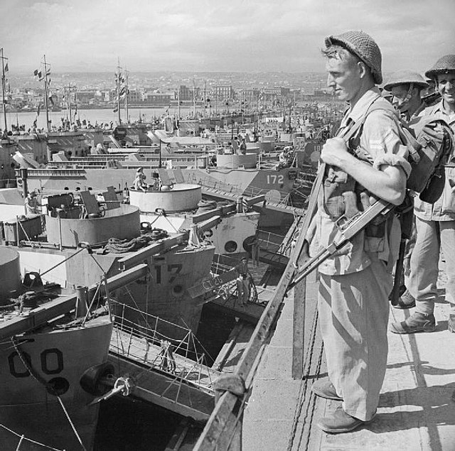 Troops from 2nd Battalion, Northamptonshire Regiment, part of the 17th Brigade of the 5th Division, wait to board landing craft at Catania, Sicily, fo