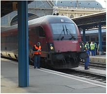 A wheeltapper signing off after checking the wheels of a train at Budapest-Keleti railway station in 2014. He has placed his long hammer on the train's buffers. A wheeltapper signing off at Budapest-Keleti.jpg