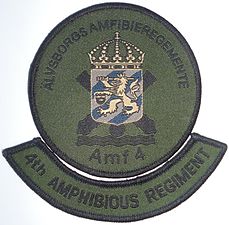 Amf 4 förbandsmärke till fältuniform. Tilläggsbågen med regementsnamnet på engelska skulle anläggas vid eventuell samövning med utländska förband.