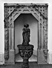Bir kadın heykelini çerçeveleyen bir portalın siyah beyaz fotoğrafı.