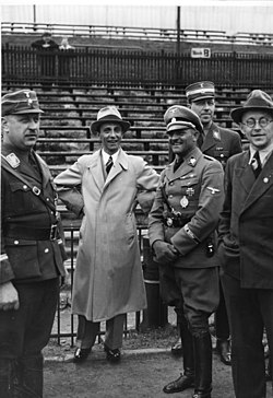 1936 photograph showing Sepp Dietrich standing 3rd from right wearing the Tank Memorial badge Bundesarchiv Bild 183-2006-1016-500, Goebbels bei Generalprobe zum 1. Mai.jpg