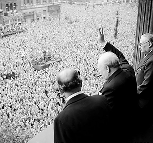 Perdana Menteri Winston Churchill memberi tanda "Victory" kepada kerumunan di London pada Hari Kemenangan di Eropa.