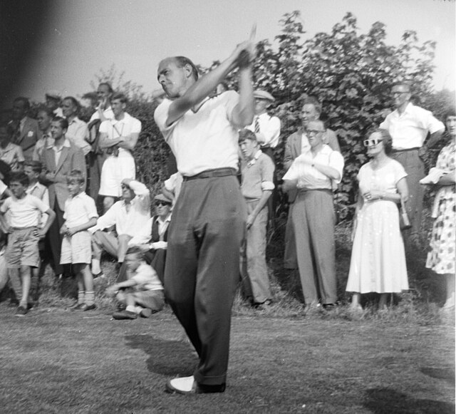 Black-and-white photograph from the front of Eric Brown which shows him finishing his golf swing over his left shoulder.