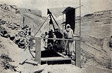 Schwarz-Weiß-Foto von Palästinensern, die die Winde über dem Brunnen bedienen.